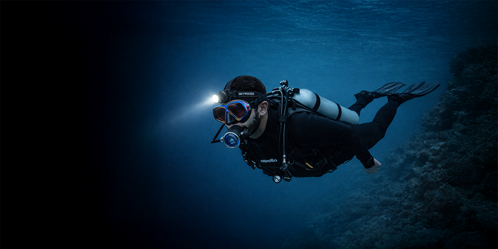 Diver wearing D6HL Skywoods dive headlamp, Apollo Bio Regulators, Apollo 60th Anniversary bio mask wwith reef in background